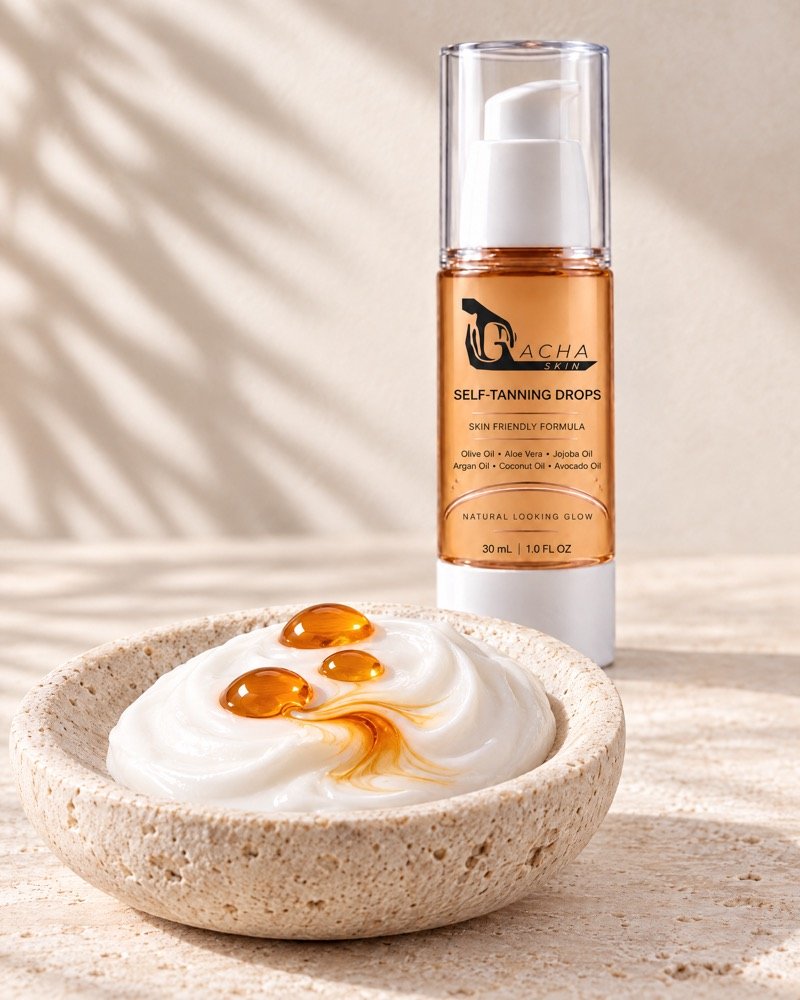 Three amber drops of Gacha Self-Tanning Drops marbling into white moisturiser in a travertine dish, with the bottle standing behind.